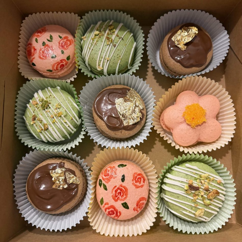 An elegant box of French macarons with painted roses, pistachio and gold leaf